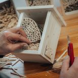Ein Mann baut ein Bienenhaus aus Holzstöcken, um Bienen einen Lebensraum zu bieten